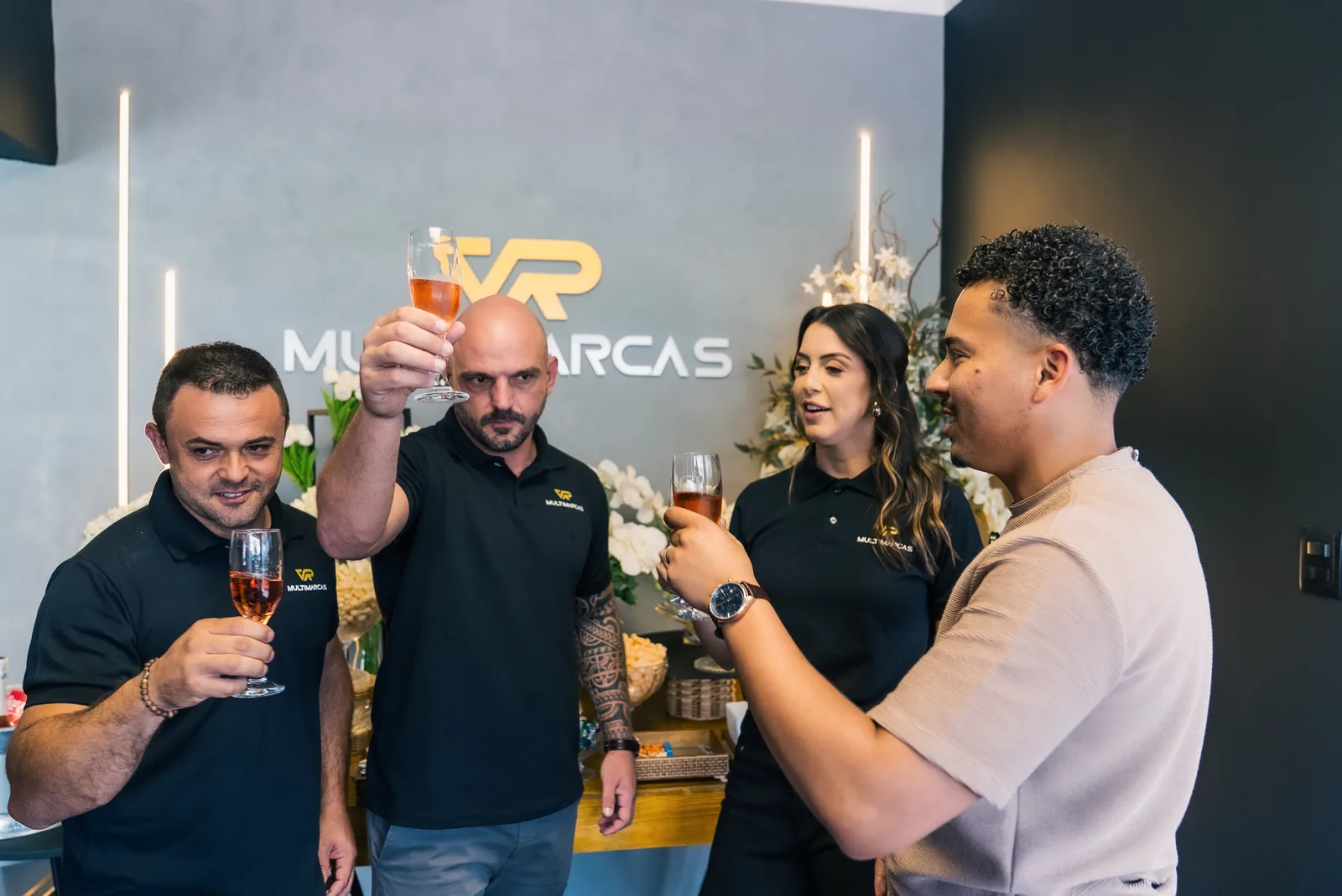 Sócios e convidados brindando na frente do logo VR Multimarcas na inauguração